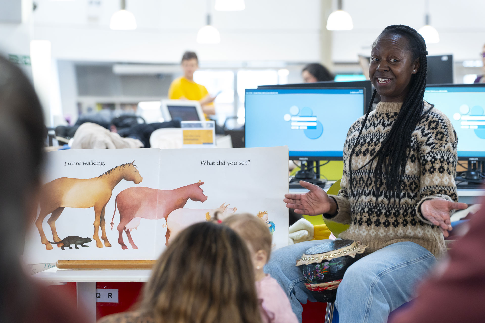 Staff member reading a children's book during a Rhyme Time session with young children at Canada Water Library.